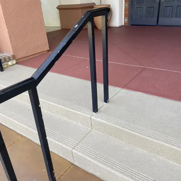 Resurfaced entry steps with a black handrail and a red bordered landing
