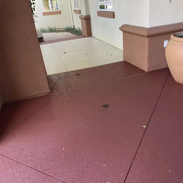 Cream and red resurfaced walkway running past a stucco column
