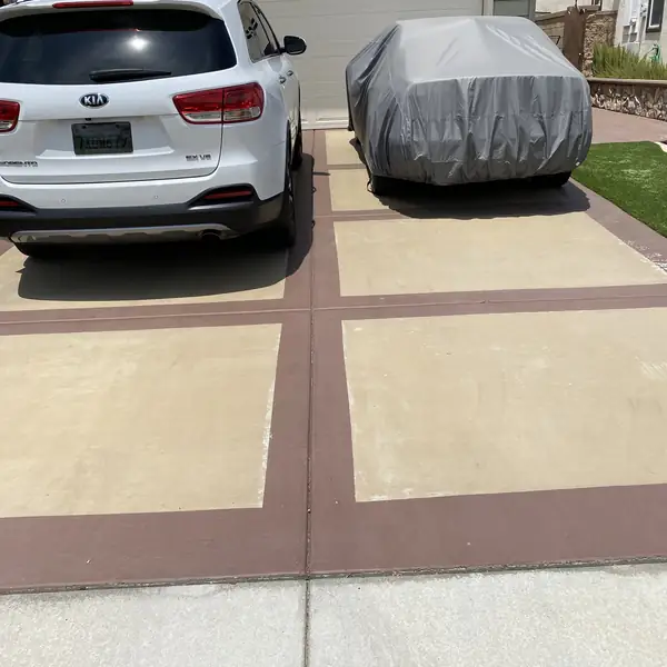 Resurfaced driveway in cream with brown banding and parked cars