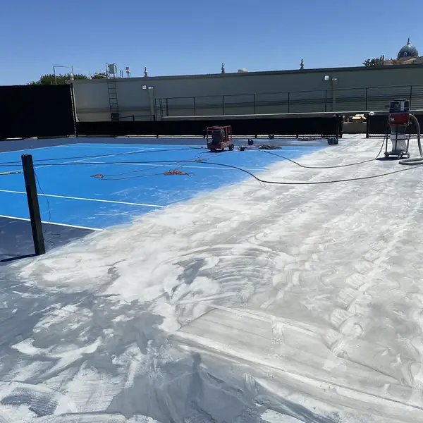 Blue sports court with a wide band of coating already ground away