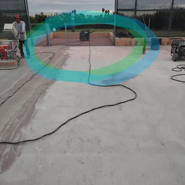 Crew grinding a pool deck with the old teal and green coating still visible