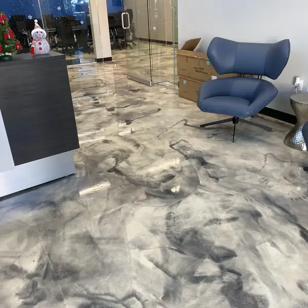 Marbled gray metallic epoxy floor in an office lounge with a blue armchair