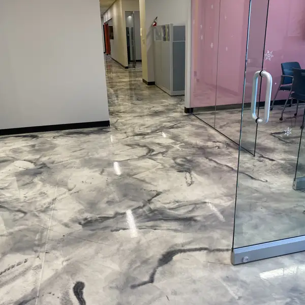 Gray and white metallic epoxy floor running down an office corridor past frosted glass