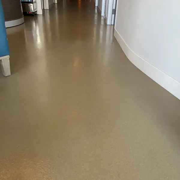 Bronze flake epoxy floor curving down a commercial hallway past a blue column