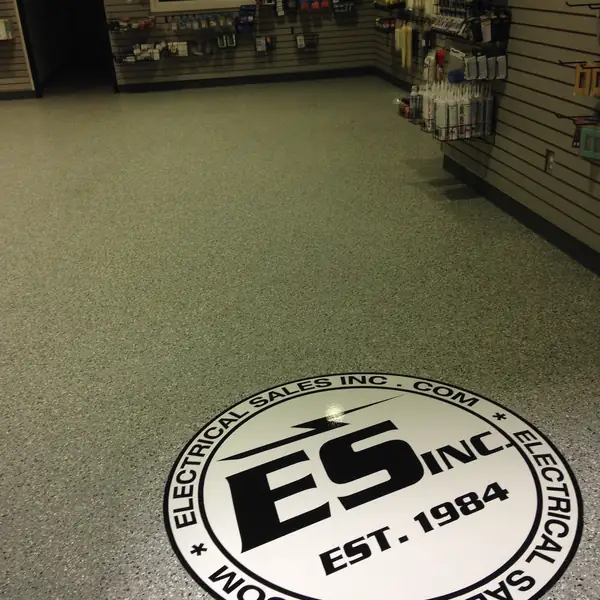 Retail store floor in olive flake epoxy with a circular company logo inlay