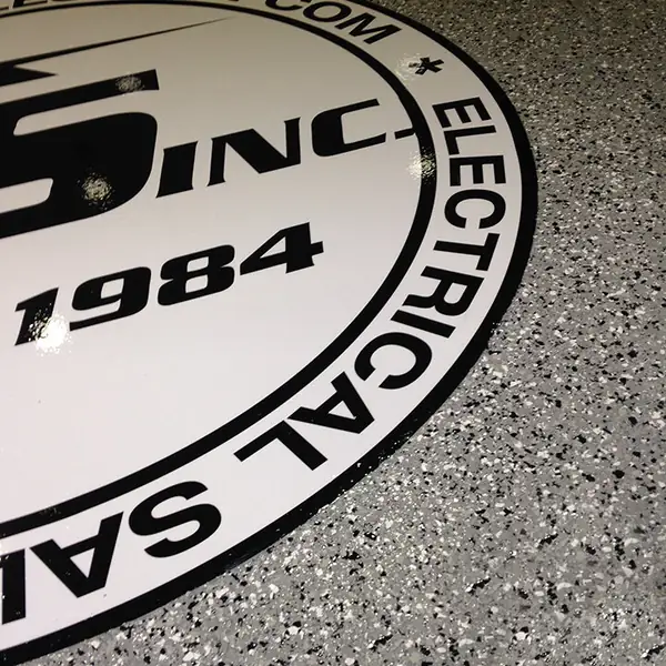 Company crest inlaid into speckled gray flake epoxy at floor level