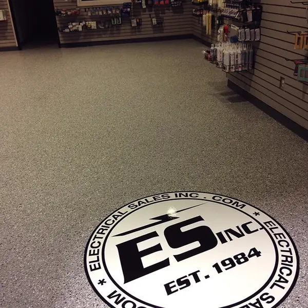 Retail sales floor in tan flake epoxy with a round logo inlay near the counter
