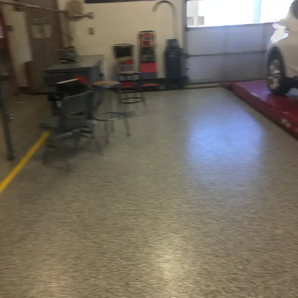 Olive flake epoxy floor in a vehicle service bay with a car on the lift