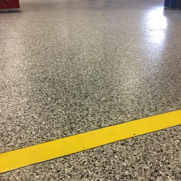 Gray flake epoxy floor with a yellow safety line running across it