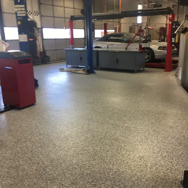 Tan flake epoxy floor running through a service shop past the vehicle lifts