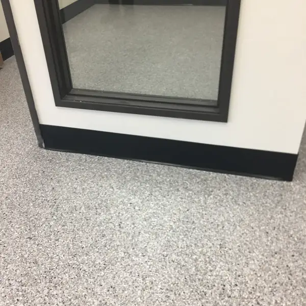 Gray flake epoxy floor meeting the base of a window display frame