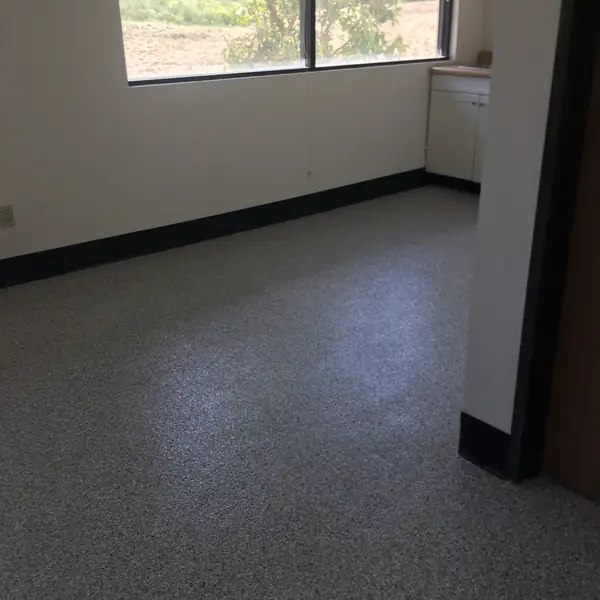 Charcoal flake epoxy floor in an empty office suite with a window to the hills