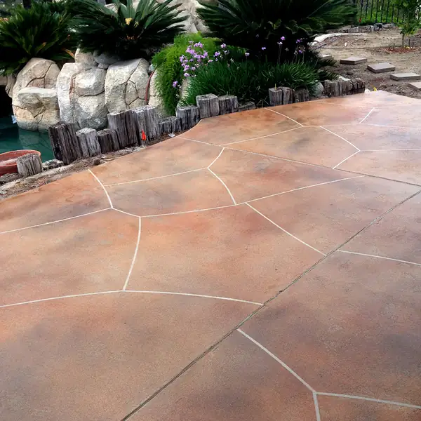 Terracotta stained patio cut in a flagstone pattern beside tropical planting