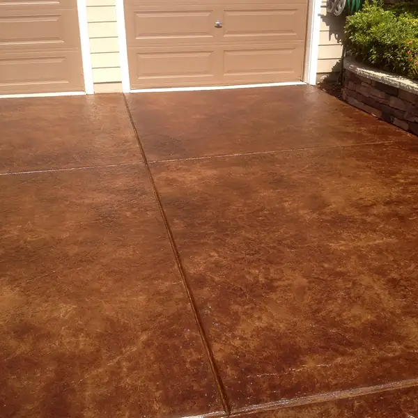 Rich brown stained driveway running up to a residential garage door