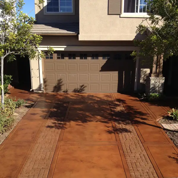 Rust stained driveway with a brick border in front of a two-story home