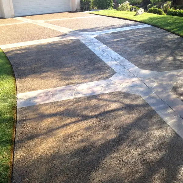 Stained driveway broken up with white banding leading to a garage