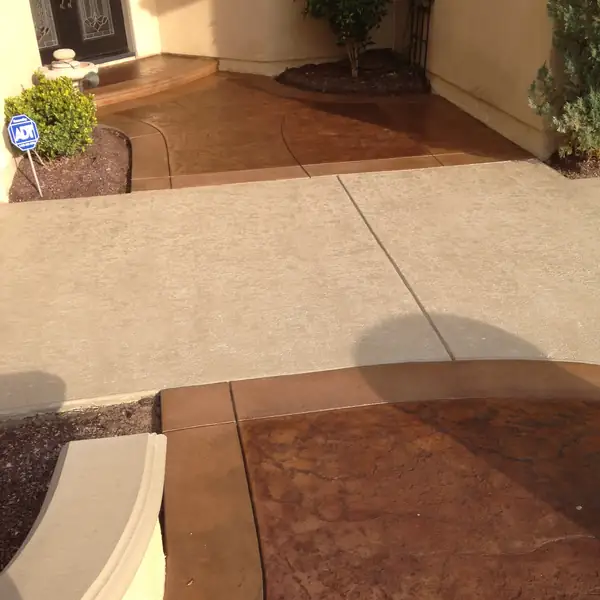 Stained front entry walkway in warm brown meeting a cream patio