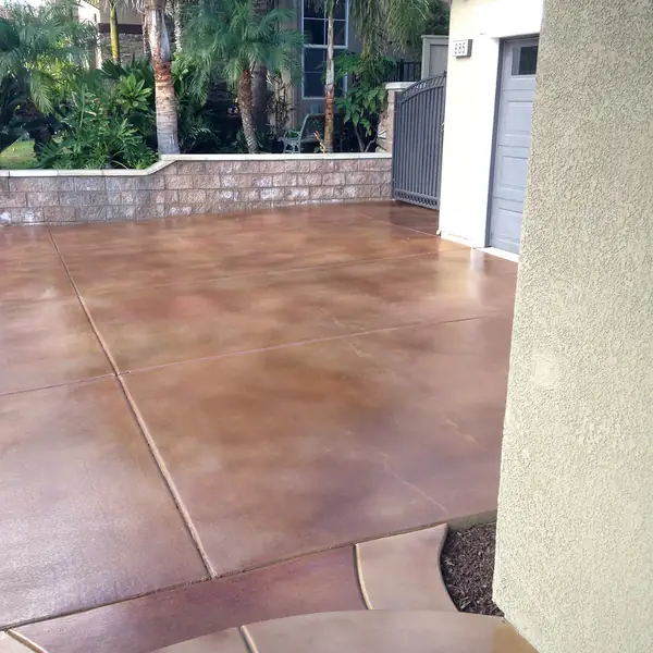 Stained side yard patio with a paver-look border against a rendered wall