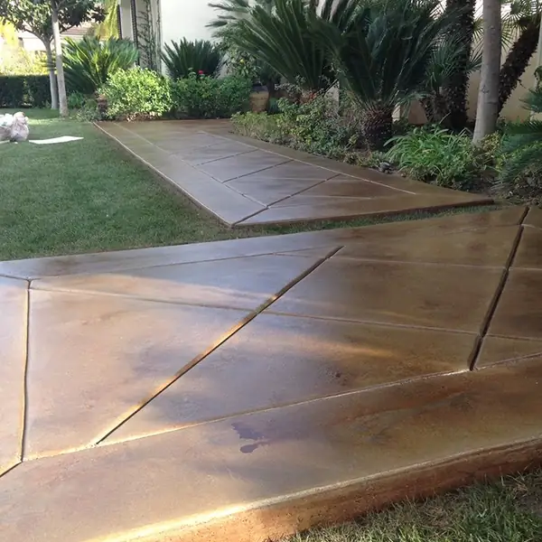 Tan stained walkway scored in a diamond pattern beside a lawn