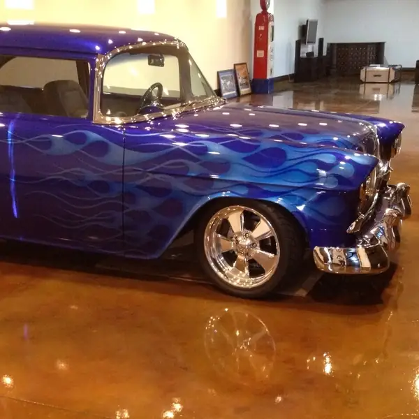 Custom blue flamed hot rod parked on a glossy copper-stained garage floor