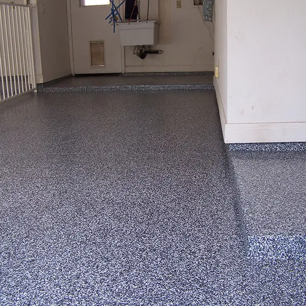 Gray and blue flake epoxy garage floor running up to the door into the house