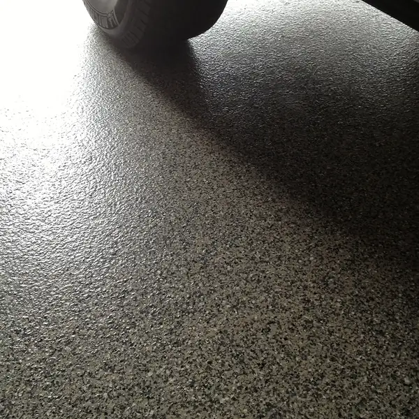 Car tire resting on a gray flake epoxy garage floor