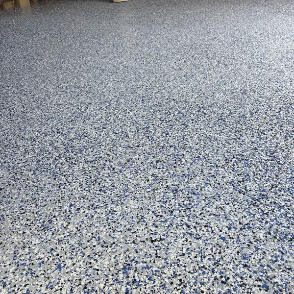Blue, white and gray flake epoxy floor in a garage still in bare wood framing