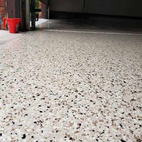 Cream, tan and black flake epoxy garage floor running out through the open door to the driveway