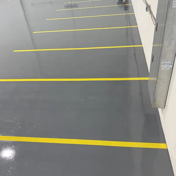 Yellow aisle lines running across a glossy gray epoxy warehouse floor