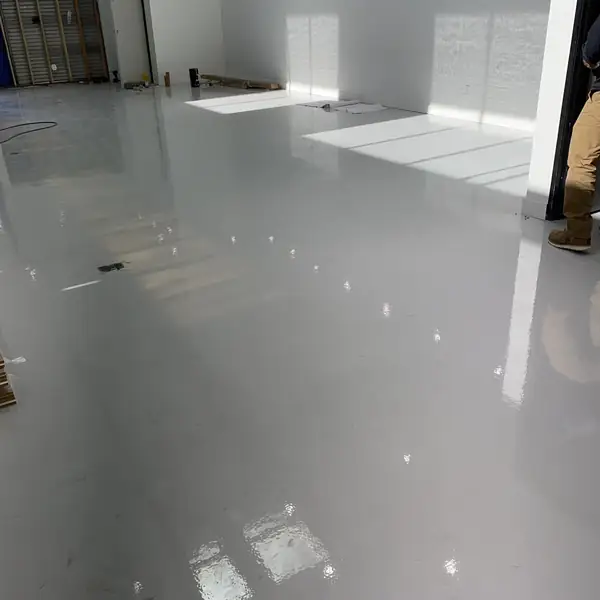 Gray epoxy floor in a bright industrial room with sunlight across it