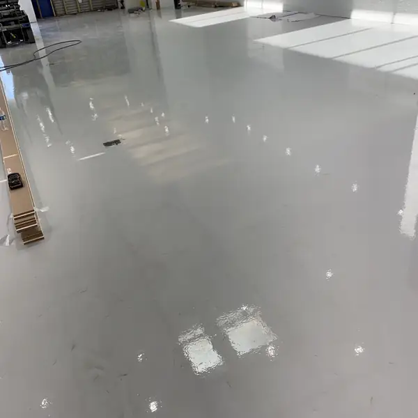 Glossy gray epoxy floor reflecting a row of high windows