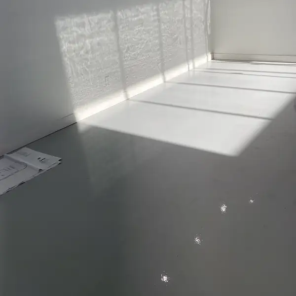 Sunlight falling across a fresh gray epoxy floor in an empty industrial unit