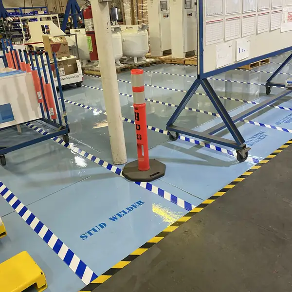 Blue and white striped safety zones marked on a pale blue epoxy plant floor