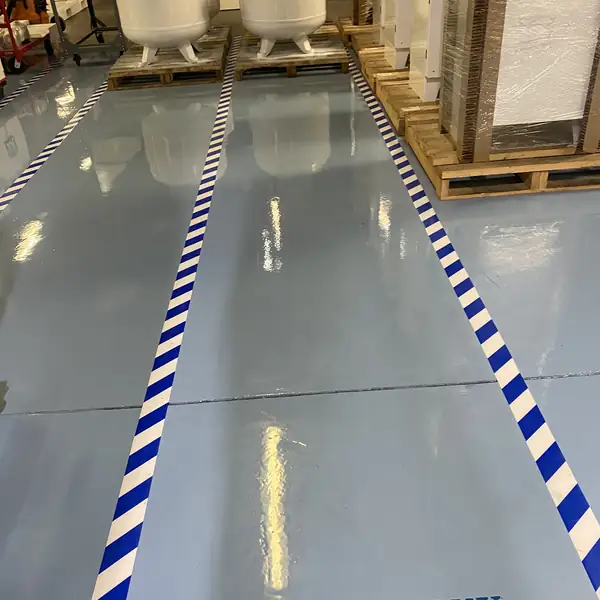 Pale blue epoxy plant floor with blue and white striped walkway lines and a stencilled label