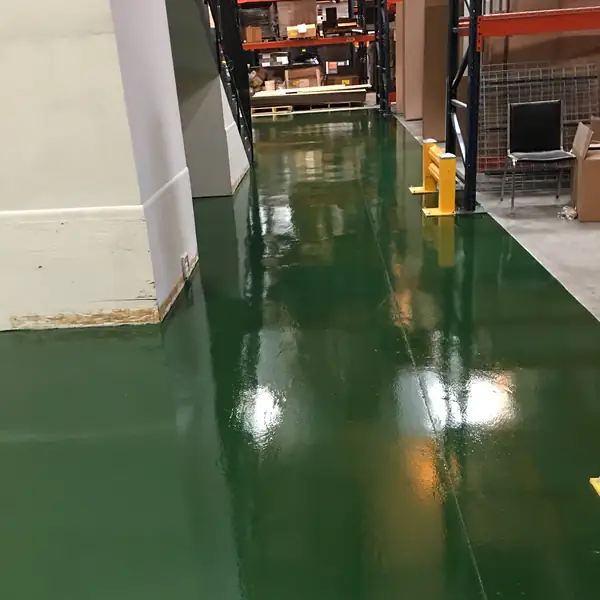 Green epoxy walkway passing warehouse racking and a yellow bollard