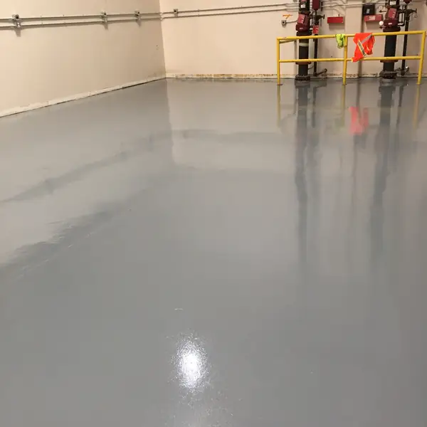 Gray epoxy floor in a warehouse bay with yellow guard rails at the far wall