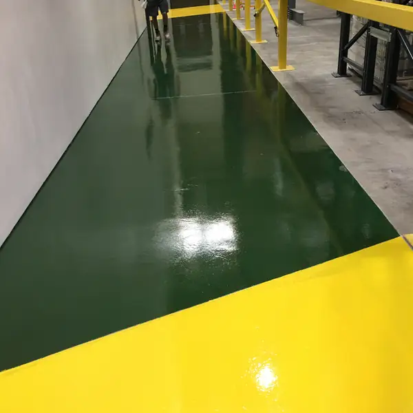 Dark green and yellow epoxy walkway cutting across a warehouse floor