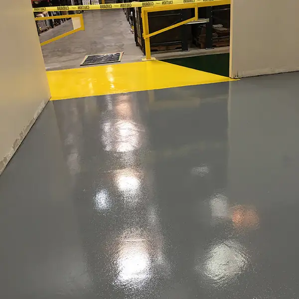 Gray warehouse epoxy floor with a single yellow line marking the walkway