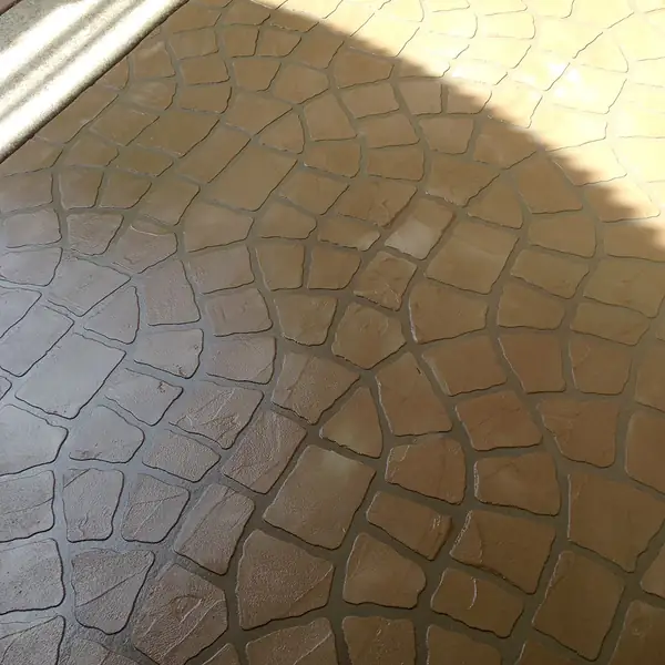 Cobblestone-pattern overlay stamped into a patio in warm brown