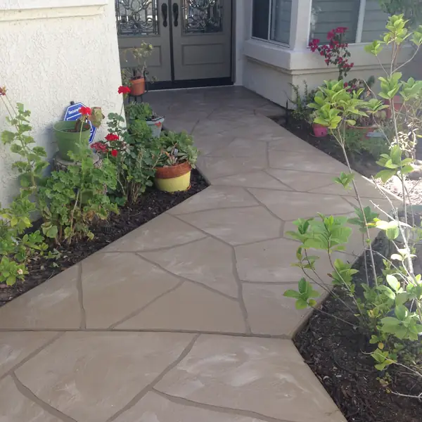 Flagstone-pattern overlay on an entry patio with planted borders