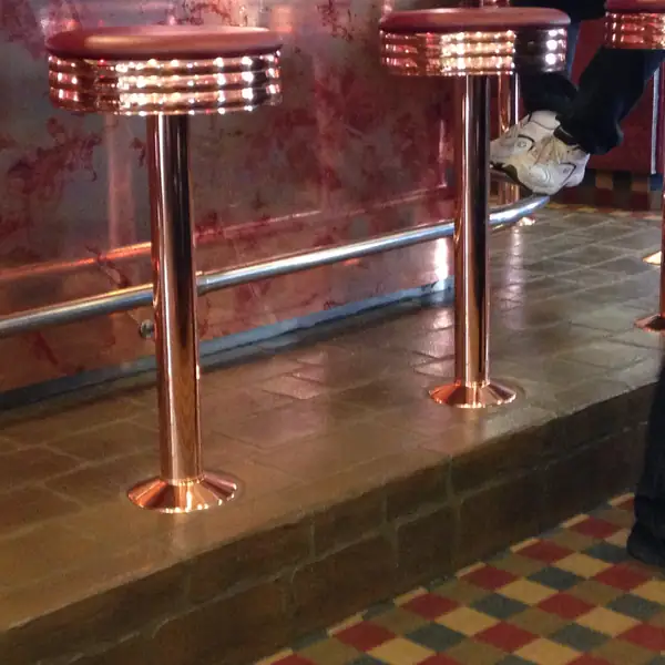 Copper bar stools on a checcurboard patterned decorative floor overlay