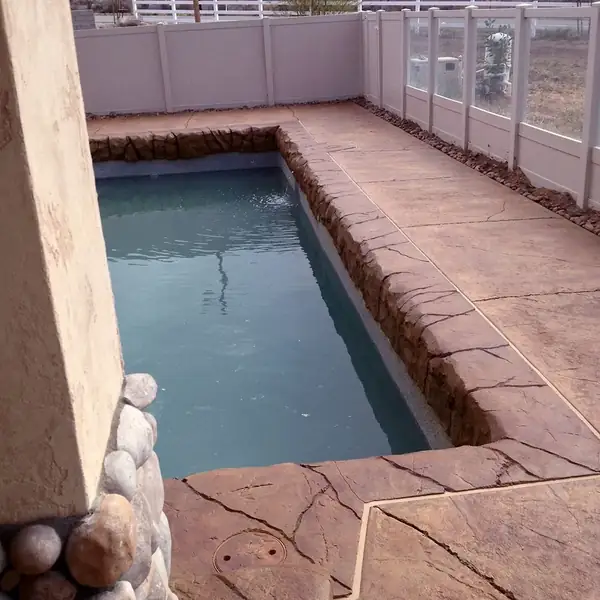 Stamped overlay deck around a rectangular spa with a tiled edge