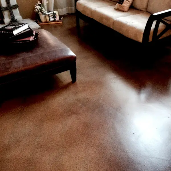 Brown stained concrete living room floor with a leather ottoman