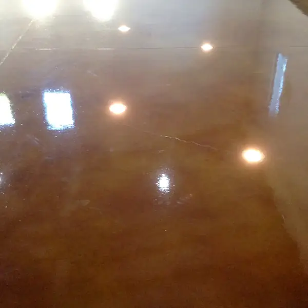 Glossy brown stained concrete floor reflecting ceiling downlights