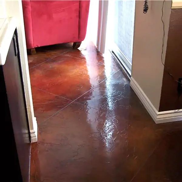 Red-brown stained concrete floor in a kitchen beside a red armchair