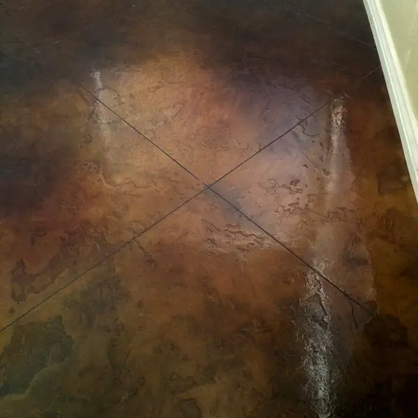 Dark brown stained concrete floor scored in a diamond pattern