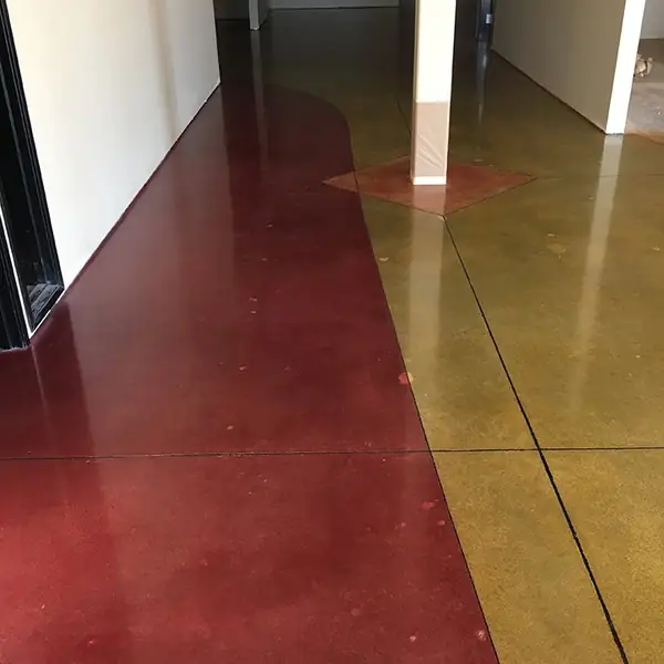 Red and gold stained concrete hallway floor with a curved color break