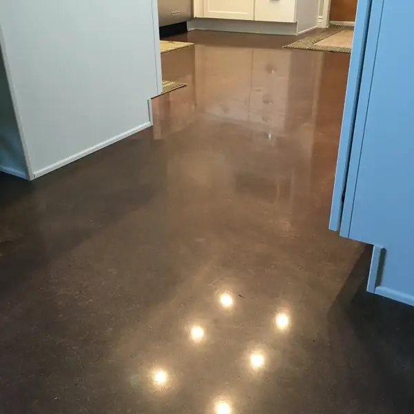 Brown stained and polished concrete floor in a kitchen with pale cabinetry