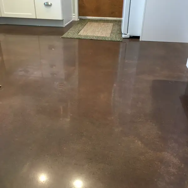 Brown polished concrete kitchen floor with rugs and appliances