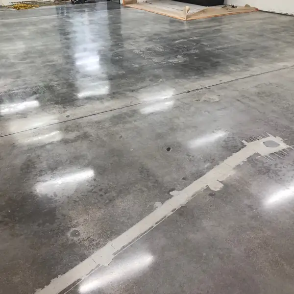 Polished gray concrete floor reflecting overhead lighting